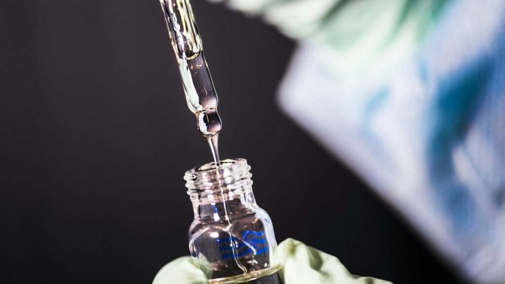 Lab technician transferring a peptide sample into a glass vial for analysis