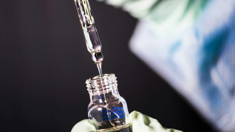 Lab technician transferring a peptide sample into a glass vial for analysis